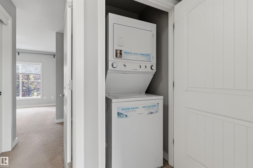 Dedicated laundry closet featuring a white stacked washer and dryer unit - #62 675 Watt Bv Sw, Edmonton, AB - Indoor Photo Showing Laundry Room