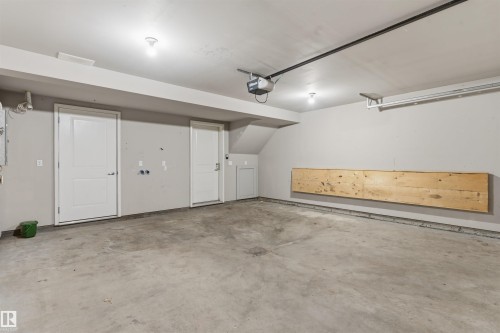 Spacious garage featuring a concrete floor, two entry doors, and a built-in wood-finish workbench - #62 675 Watt Bv Sw, Edmonton, AB - Indoor Photo Showing Garage