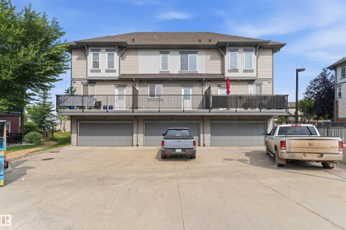 Multi-level townhouse exterior featuring light-toned siding and dark trim accents - #62 675 Watt Bv Sw, Edmonton, AB - Outdoor With Balcony