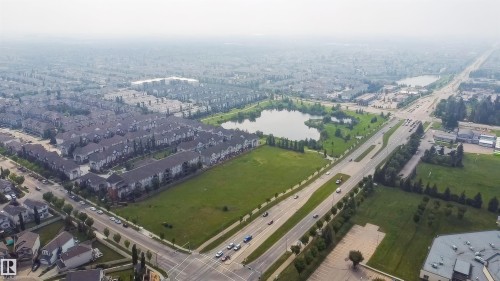 Expansive aerial view showcasing a large undeveloped green space bordered by residential developments and a multi-lane road - #62 675 Watt Bv Sw, Edmonton, AB - Outdoor With View