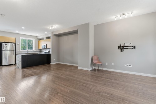 Open-concept living space featuring wood-finish flooring and neutral wall tones - #62 675 Watt Bv Sw, Edmonton, AB - Indoor