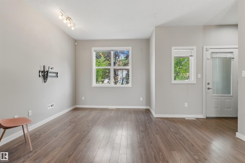 Spacious room featuring wood-finish flooring, white baseboards, and neutral wall paint - #62 675 Watt Bv Sw, Edmonton, AB - Indoor Photo Showing Other Room