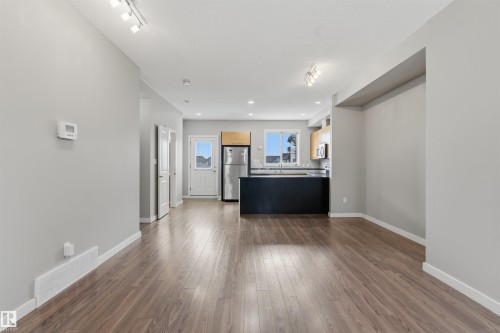 Open-concept living area with wood-finish flooring, recessed lighting, track lighting, and light grey wall finishes - #62 675 Watt Bv Sw, Edmonton, AB - Indoor Photo Showing Other Room