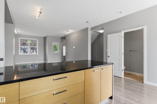 Kitchen island featuring light wood-finish cabinetry and a dark countertop - #62 675 Watt Bv Sw, Edmonton, AB - Indoor Photo Showing Other Room