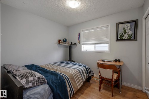Light wood-finish flooring, a window with white blinds, and a built-in wall shelf - 9113 166 Avenue Nw, Edmonton, AB - Indoor Photo Showing Bedroom