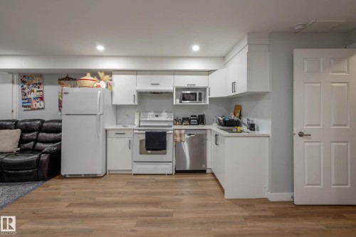 Kitchenette featuring white cabinetry, light countertops, wood-finish flooring, recessed lighting, and a stainless steel dishwasher - 9113 166 Avenue Nw, Edmonton, AB - Indoor Photo Showing Kitchen