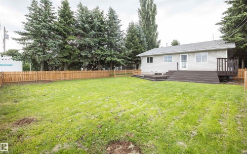 Rear exterior featuring light-colored siding, a multi-level dark-toned deck, and a privacy fence - 5116 51 Avenue, Pickardville, AB - Outdoor
