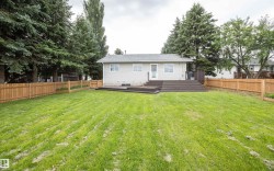 Expansive backyard featuring a new privacy fence, mature perimeter trees, a multi-level deck with dark composite decking, and a rear entrance - 