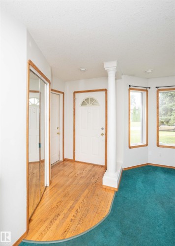 Entryway featuring wood-finish flooring, a white paneled front door with an arched window, and a decorative column - 5116 51 Avenue, Pickardville, AB - Indoor Photo Showing Other Room