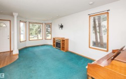 Bright living space featuring a bay window, wood-finish flooring, and an electric fireplace with built-in shelving - 