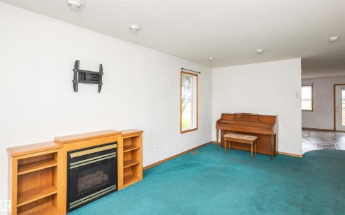 Living area featuring a fireplace with built-in shelving, recessed lighting, and a window with wood trim - 5116 51 Avenue, Pickardville, AB - Indoor With Fireplace