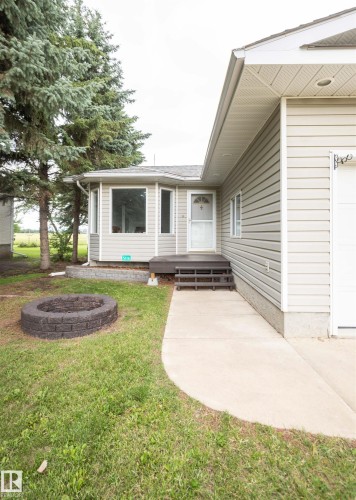 Exterior featuring light-colored horizontal siding, a bay window with white trim, and mature evergreen trees - 5116 51 Avenue, Pickardville, AB - Outdoor