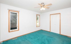 Spacious room featuring dual windows with wood-finish trim, a ceiling fan with integrated lighting, and bi-fold closet doors - 