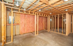Framed lower level featuring exposed wood joists, concrete flooring, and an electrical panel - 
