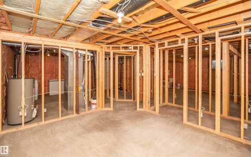 Unfinished basement featuring wood framing for multiple rooms, exposed ceiling joists with insulation, a water heater, and concrete flooring - 5116 51 Avenue, Pickardville, AB - Indoor Photo Showing Basement