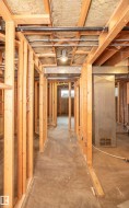 Unfinished basement space featuring rough-in framing, exposed ceiling joists with insulation, concrete flooring, and visible utility lines - 