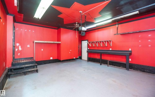 Spacious interior featuring a concrete floor, red walls, and a black ceiling with red starburst detailing - 5116 51 Avenue, Pickardville, AB - Indoor Photo Showing Other Room
