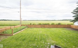 Expansive fenced backyard featuring a wood privacy fence, a dedicated garden area, and a large grassy lawn - 