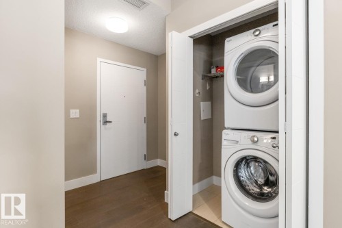 Stacked Washer & Dryer In Cupboard Just Off Kitchen. - #203 10006 83 Av Nw, Edmonton, AB - Indoor Photo Showing Laundry Room