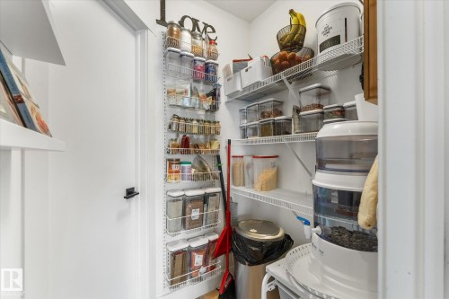Pantry featuring white walls, wire shelving, and a white interior door with a black handle - 6875 Evans Wynd Nw, Edmonton, AB - Indoor