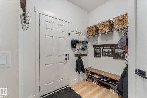 Entryway featuring a paneled door with matte black hardware, wood-finish flooring, and white walls - 6875 Evans Wynd Nw, Edmonton, AB - Indoor Photo Showing Other Room