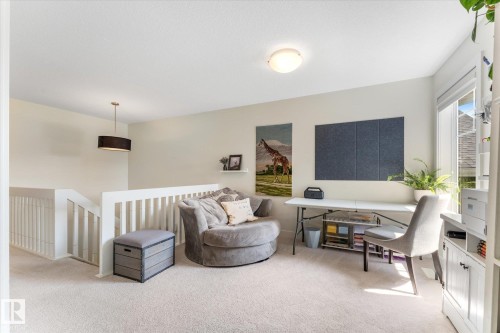 Carpeted loft area featuring a white spindle railing, a contemporary drum pendant light, a recessed ceiling light, and a window providing natural illumination - 6875 Evans Wynd Nw, Edmonton, AB - Indoor