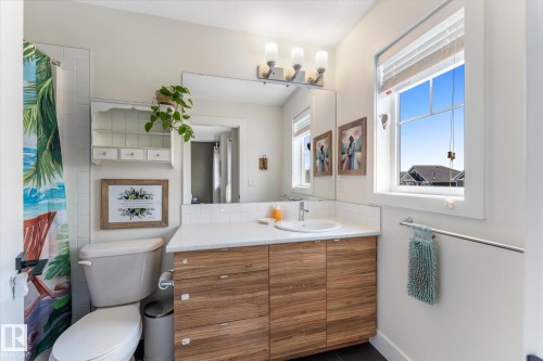 Full vanity featuring wood-finish cabinetry, a white countertop, and an integrated sink - 6875 Evans Wynd Nw, Edmonton, AB - Indoor Photo Showing Bathroom