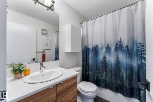 Bathroom featuring a modern vanity with wood-finish cabinetry, a white countertop, and an oval undermount sink with a chrome faucet - 6875 Evans Wynd Nw, Edmonton, AB - Indoor Photo Showing Bathroom