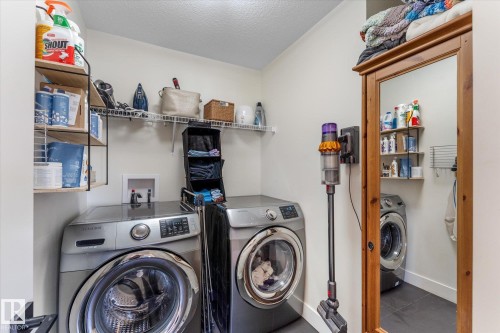 Dedicated laundry area featuring a tile floor, white walls, and built-in wire shelving - 6875 Evans Wynd Nw, Edmonton, AB - Indoor Photo Showing Laundry Room