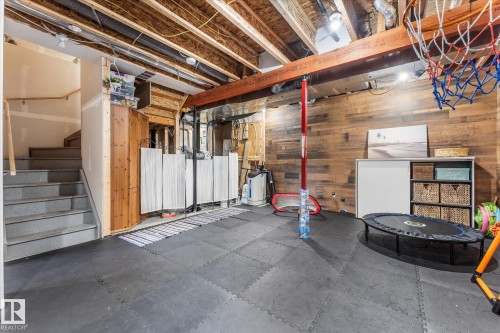 Lower level featuring exposed ceiling joists, wood plank wall paneling, modular floor tiling, and a finished staircase with handrail - 6875 Evans Wynd Nw, Edmonton, AB - Indoor Photo Showing Basement