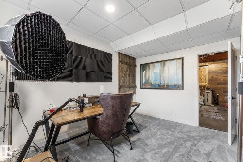 Carpeted room featuring a drop ceiling, white walls, and a barn door - 6875 Evans Wynd Nw, Edmonton, AB - Indoor
