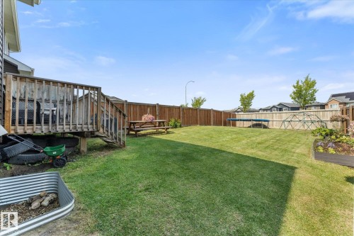 Expansive backyard featuring a manicured lawn, full wood fencing, and a wooden deck with railing - 6875 Evans Wynd Nw, Edmonton, AB - Outdoor With Backyard