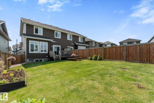 Expansive backyard featuring a manicured lawn, a wooden deck, and a full privacy fence - 6875 Evans Wynd Nw, Edmonton, AB - Outdoor With Exterior
