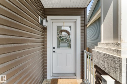 Entryway featuring a white door with upper glass panel, dark hardware, and a white trim surround - 6875 Evans Wynd Nw, Edmonton, AB -  With Exterior