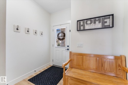 Entryway featuring wood-finish flooring, a white paneled door with a glass insert, and clean white walls - 6875 Evans Wynd Nw, Edmonton, AB - Indoor Photo Showing Other Room