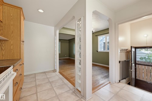 Kitchen area featuring tiled flooring, wood cabinetry, and a built-in oven - 7754 80 Avenue Nw, Edmonton, AB - Indoor