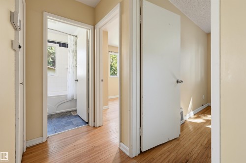 Interior hallway featuring wood-finish flooring, light-toned walls, and white trim - 7754 80 Avenue Nw, Edmonton, AB - Indoor Photo Showing Other Room