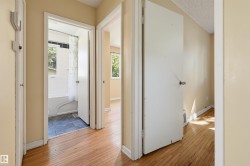 Interior hallway featuring wood-finish flooring, light-toned walls, and white trim - 