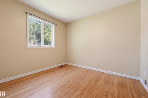 Hardwood flooring and light beige walls define this room, featuring a white-framed window - 7754 80 Avenue Nw, Edmonton, AB - Indoor Photo Showing Other Room