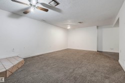 Expansive carpeted room featuring a ceiling fan with light fixture, recessed lighting, and a ceramic tile-finished architectural element - 