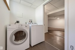 Dedicated laundry area featuring wood-finish flooring, white walls, and a drop ceiling - 