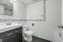 Bathroom featuring a dark wood-finish vanity with an integrated white sink, chrome faucet, and a wall-mounted mirror - 