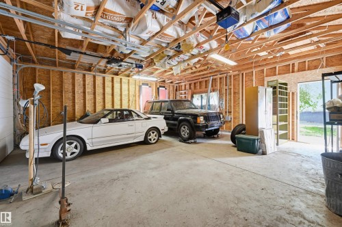 Spacious two-car garage featuring a concrete floor, exposed wood framing, and overhead fluorescent lighting - 7754 80 Avenue Nw, Edmonton, AB - Indoor Photo Showing Garage