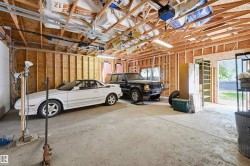 Spacious two-car garage featuring a concrete floor, exposed wood framing, and overhead fluorescent lighting - 