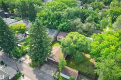 Aerial depiction showcasing a property with a brown shingle roof, a detached garage structure, and a fenced yard with a grass lawn - 
