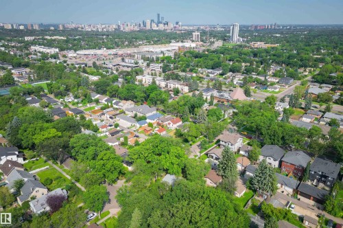 Expansive aerial perspective showcasing a residential neighborhood with a variety of architectural styles, mature tree canopy, and distant city skyline - 7754 80 Avenue Nw, Edmonton, AB - Outdoor With View