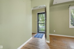 Entryway featuring an arched opening, wood-finish flooring, and a glass-paneled storm door - 