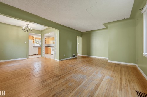 Hardwood flooring spans this room with light green walls and white trim - 7754 80 Avenue Nw, Edmonton, AB - Indoor Photo Showing Other Room