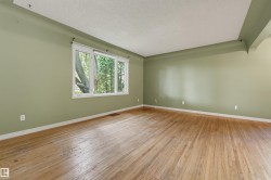 Hardwood flooring throughout a room with a large window, white trim, and a high ceiling - 