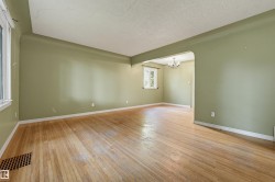 Expansive living area featuring wood-finish flooring, light green wall paint, and white trim - 